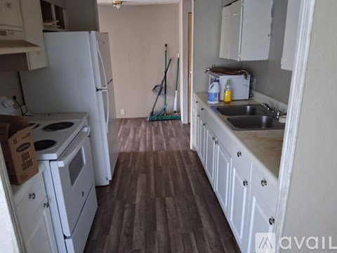 A kitchen with white appliances and wooden floors.
