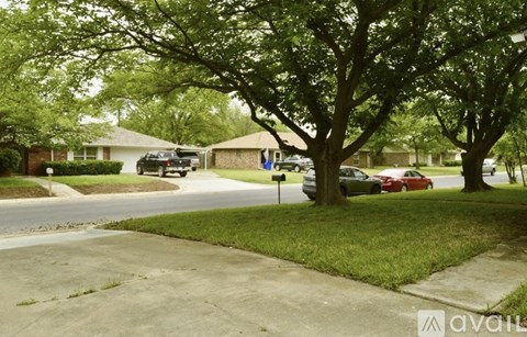 A tree in a grassy area with a house in the background.