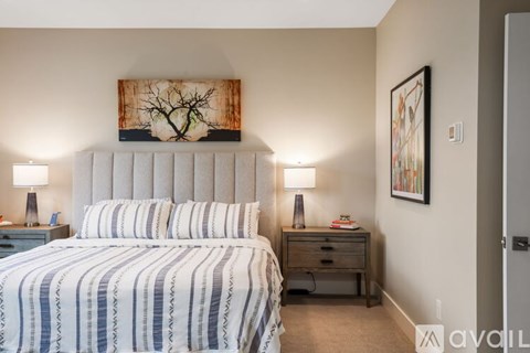 A bedroom with a large bed and a painting on the wall.