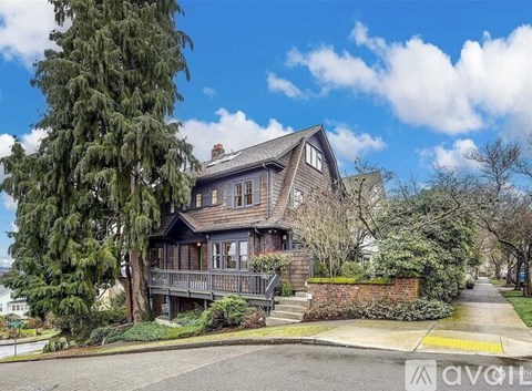 A house with a porch and a tree in front.