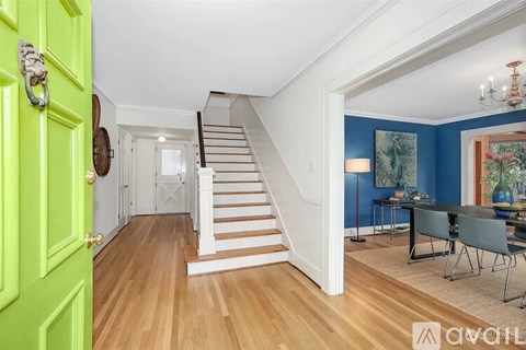 A bright green door is on the left of a staircase with white railings.