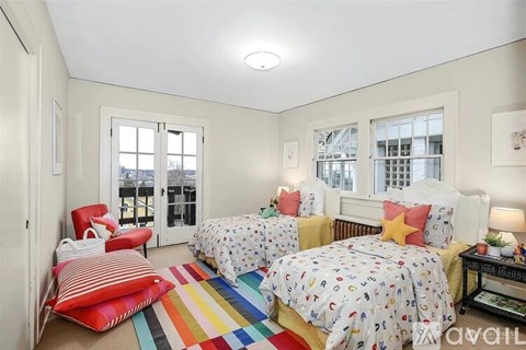 A bedroom with two beds and a red chair.
