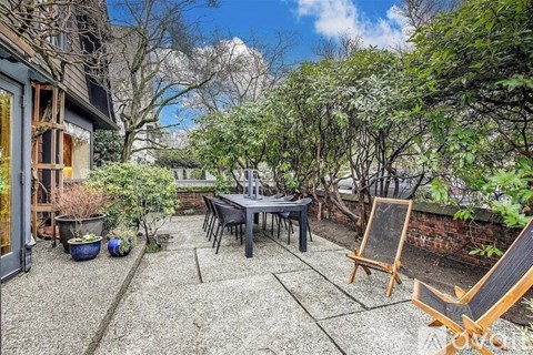 A patio with a table and chairs surrounded by trees.
