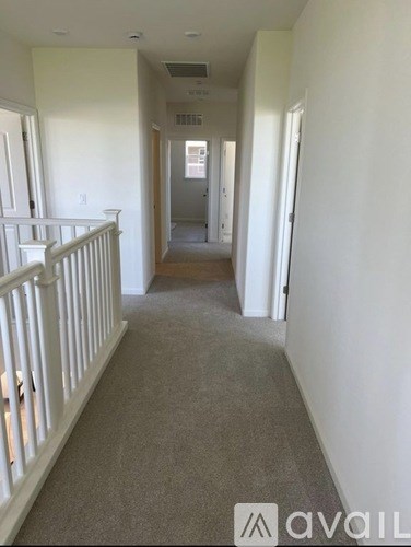A hallway with a carpeted floor and white railings.