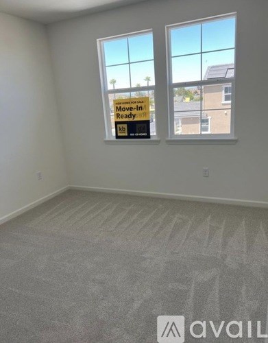 A room with a carpeted floor and a window that has a sign that says "Move-in Ready".
