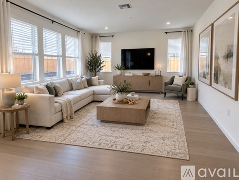 A living room with a white couch, a coffee table, and a flat screen TV mounted on the wall.