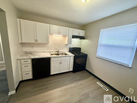A kitchen with white cabinets and black appliances.