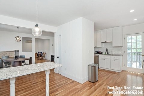 A kitchen with white cabinets and a marble island.