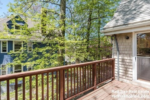 A wooden deck with a house and trees in the background.