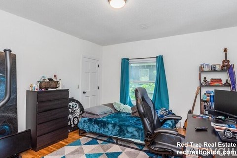 A bedroom with a bed, desk, and chair.
