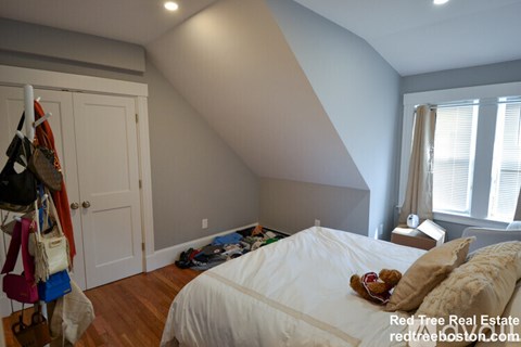 A bedroom with a bed, pillows, and a coat rack.