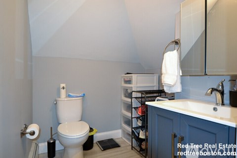 A bathroom with a toilet, sink, and a towel hanging on the wall.