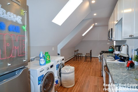 A washing machine is on top of a dryer in a kitchen.