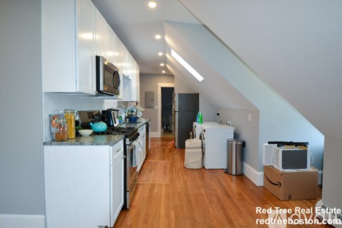 A kitchen with white cabinets and a wooden floor.