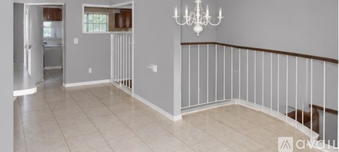 A living room with a chandelier and a balcony with white railings.