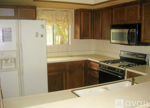 A kitchen with a white fridge, white countertop, and a black microwave above the stove.