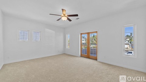A spacious room with a ceiling fan and beige carpeting.