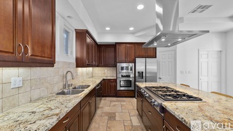 A kitchen with brown cabinets and granite countertops.