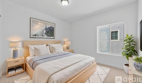 A bedroom with a large bed and a framed picture on the wall.