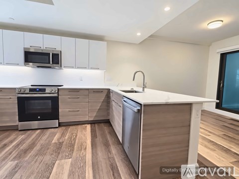 A modern kitchen with wooden flooring and stainless steel appliances.