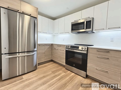 A kitchen with a stainless steel refrigerator, microwave, and oven.
