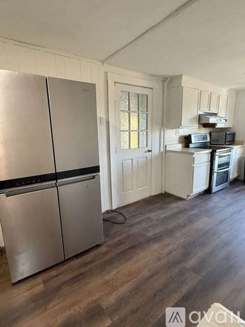 A kitchen with a stainless steel refrigerator and wooden floors.