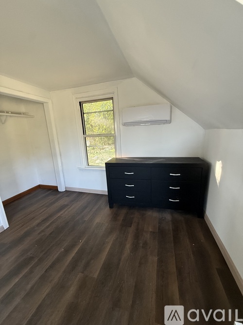 A room with a black dresser and wooden flooring.