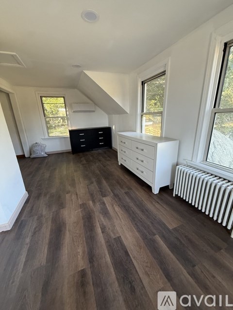 A room with wooden flooring and white furniture.