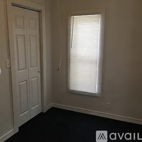 A room with a white door and a window with blinds.