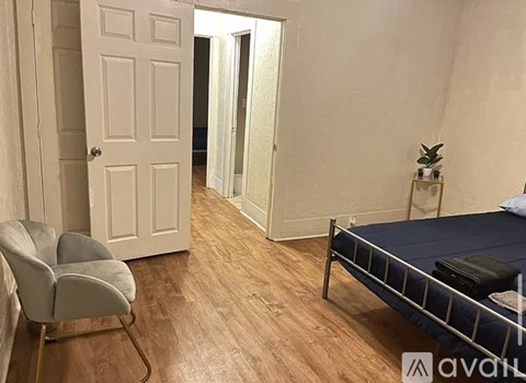 A bedroom with a bed, chair, and a door.