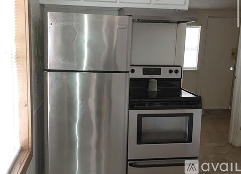 A stainless steel refrigerator stands in a kitchen next to a white oven.