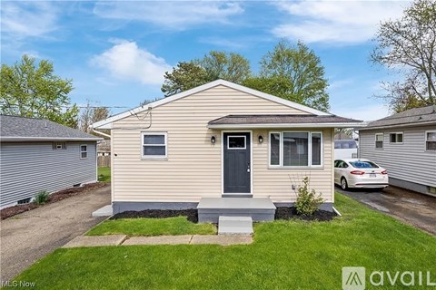 A beige house with a black door and a small front yard.