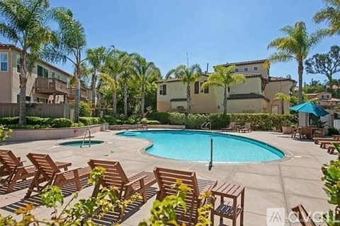 A pool surrounded by wooden chairs and palm trees.