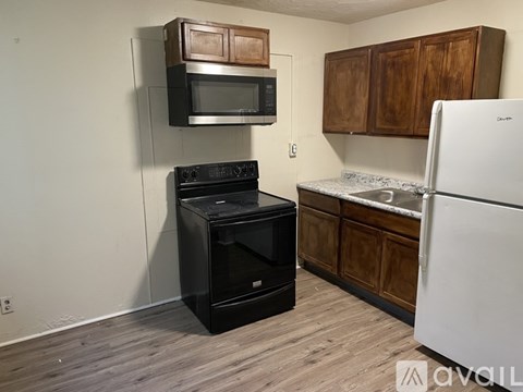 A kitchen with a white fridge, black oven, and microwave above it.