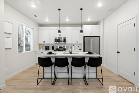 A kitchen with white cabinets and a center island with four black chairs.
