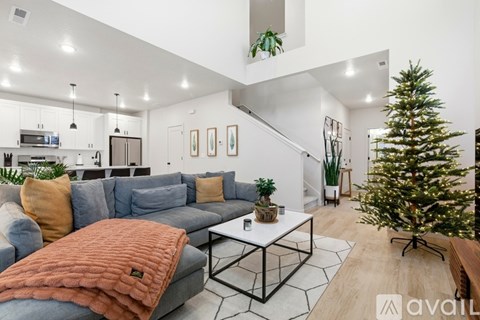 A living room with a grey couch and a Christmas tree.