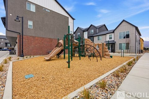 A playground with a slide and swings in front of a building.