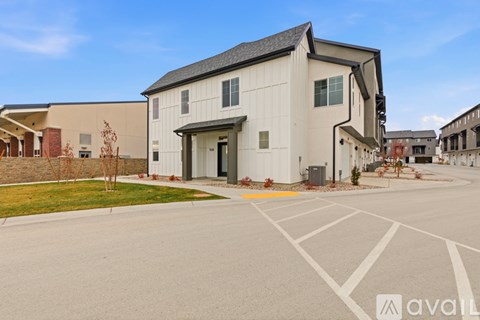A modern building with a white exterior and a large garage door is surrounded by a parking lot.