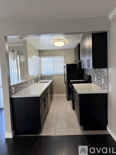 A modern kitchen with black cabinets and a white countertop.