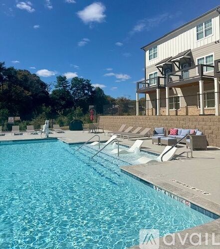 A swimming pool with lounge chairs and a building in the background.