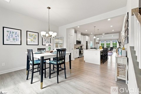 A dining room with a table set for four and a kitchen in the background.