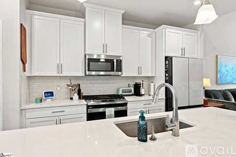 A kitchen with white cabinets and a stainless steel sink.