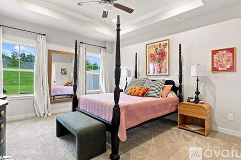 A bedroom with a four poster bed and a window overlooking a green lawn.