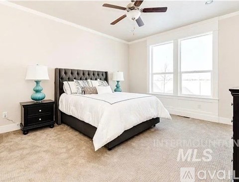 A bedroom with a large bed and a ceiling fan.