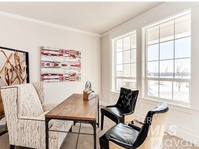 A room with a table, two chairs and a painting on the wall.