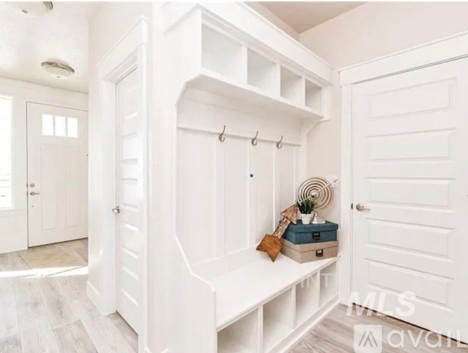 A white mudroom with a bench and hooks.
