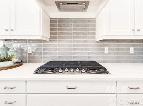 A modern kitchen with a white countertop and a black stove top.