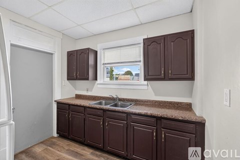 A kitchen with brown cabinets and a window overlooking a street.