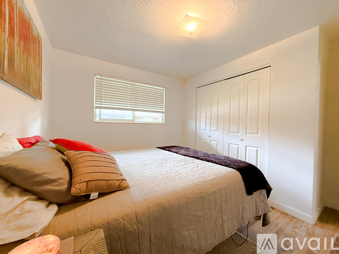 A bedroom with a bed, pillows, and a painting on the wall.