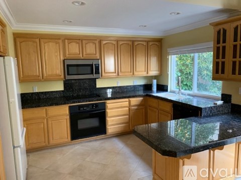A kitchen with wooden cabinets and black countertops.